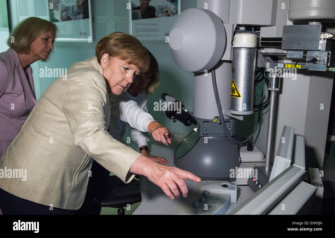 Dresde, Allemagne. 14 juillet, 2015. La chancelière allemande, Angela Merkel (CDU) ressemble à un microscope électronique à transmission au cours d'une visite à un géant des semi-conducteurs Infineon Technologies Usine à Dresde le 14 juillet 2015. À gauche est l'allemand de l'éducation et de la recherche Ministre Johanna Wanka (CDU). Photo : JOHN MACDOUGALL/dpa/Alamy Live News Banque D'Images