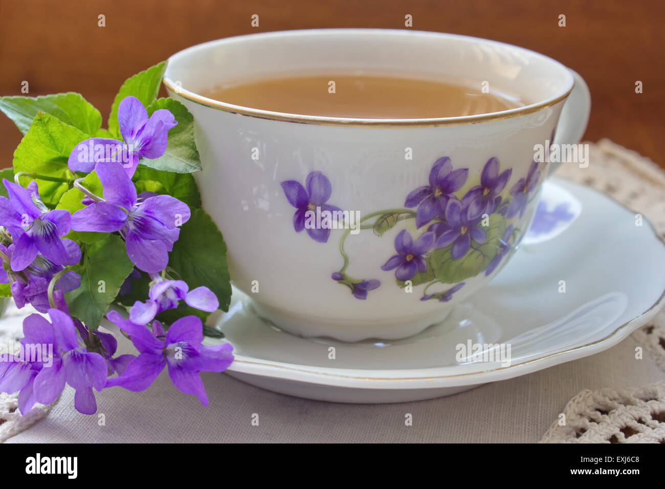 China tea cup avec le modèle de violettes et le bouquet de violettes sur la nappe blanche Banque D'Images