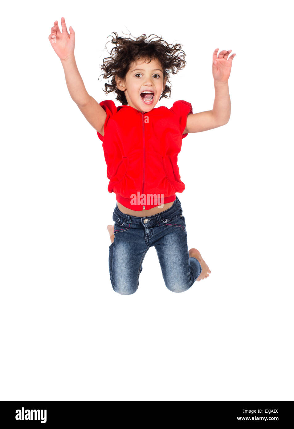 Adorable petit caucasien enfant avec des cheveux bouclés portant un haut à capuchon rouge et bleu jeans. La jeune fille saute et souriant. Banque D'Images