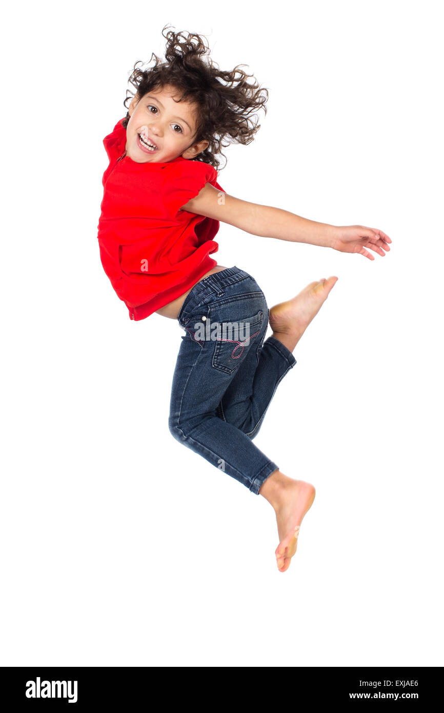 Adorable petit caucasien enfant avec des cheveux bouclés portant un haut à capuchon rouge et bleu jeans. La jeune fille saute et souriant. Banque D'Images
