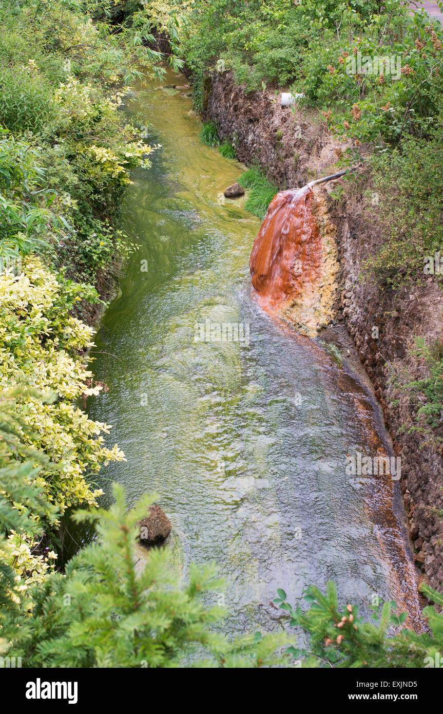 Un printemps de l'eau riche en minéraux des roches de coloration à la ville thermale de Châtel-Guyon, Puy-de-Dôme, Auvergne, France, Europe Banque D'Images
