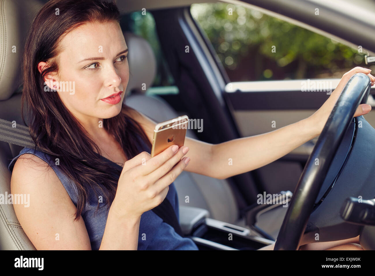 Femme à l'aide de téléphone mobile pendant la conduite Banque D'Images