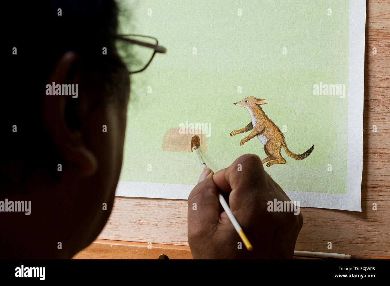 Man painting personnage animal sur papier Banque D'Images