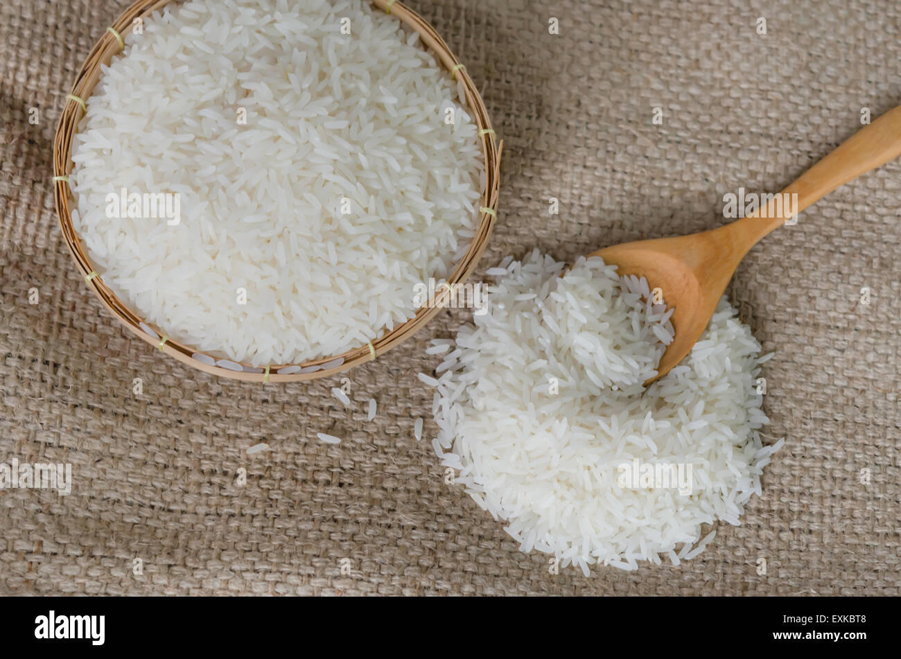 Les grains de riz blanc avec cuillère en bois sur le sac Banque D'Images