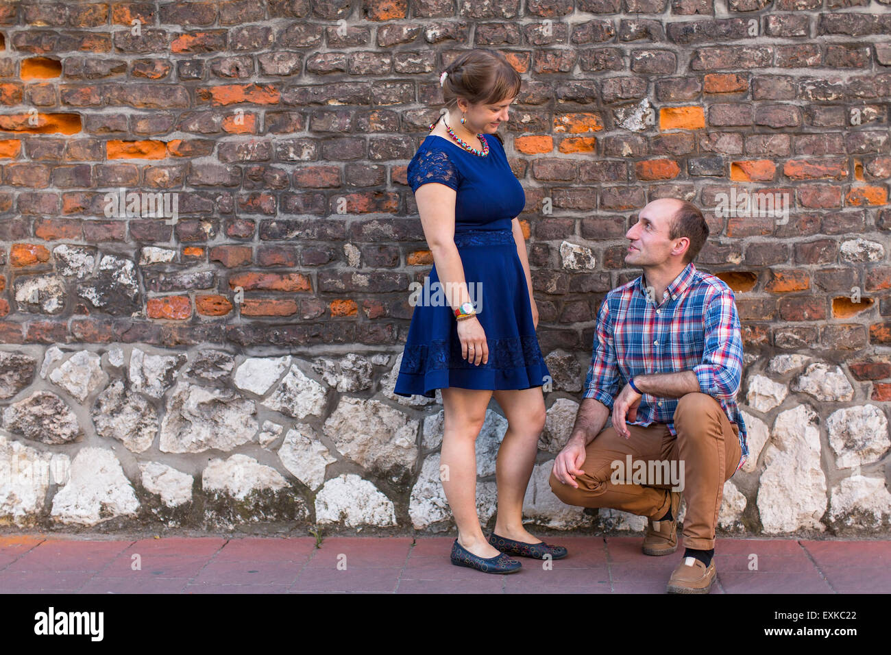 Jeune couple sympathique. Couple in love comité permanent à l'extérieur sur un mur arrière-plan. Banque D'Images