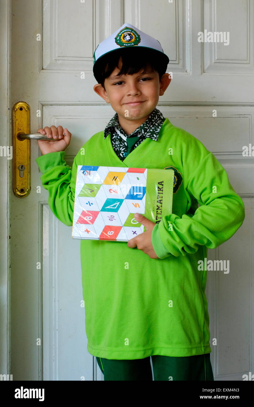 Petit garçon vêtu de son uniforme de l'école arrive à la maison portant ses livres en Indonésie java Banque D'Images