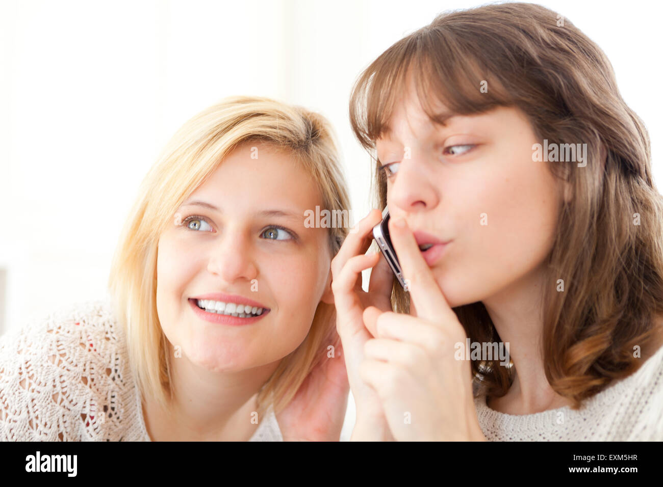 Avis d'une fille blonde essaie d'écouter une conversation dans un smartphone Banque D'Images