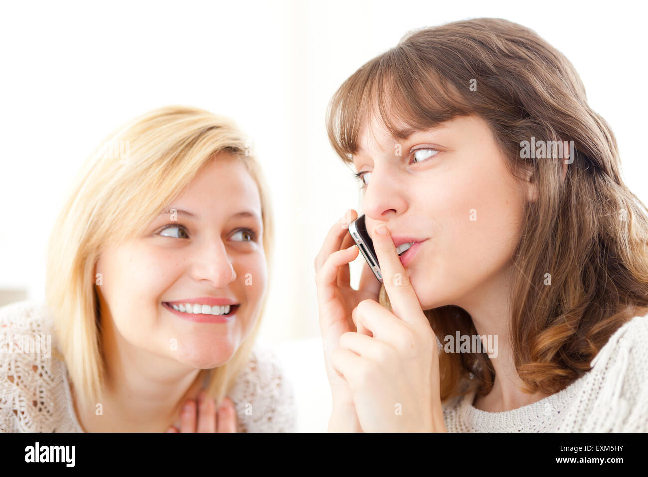 Avis d'une fille blonde essaie d'écouter une conversation dans un smartphone Banque D'Images