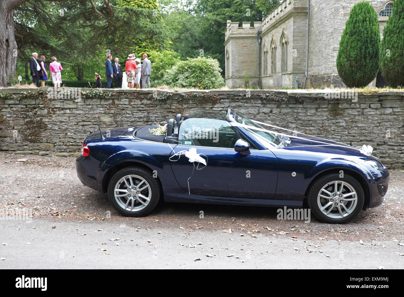 Voiture de sport Mazda MX-5 comme une voiture de mariage sur un jour de mariage avec des rubans d'une église du village UK Banque D'Images