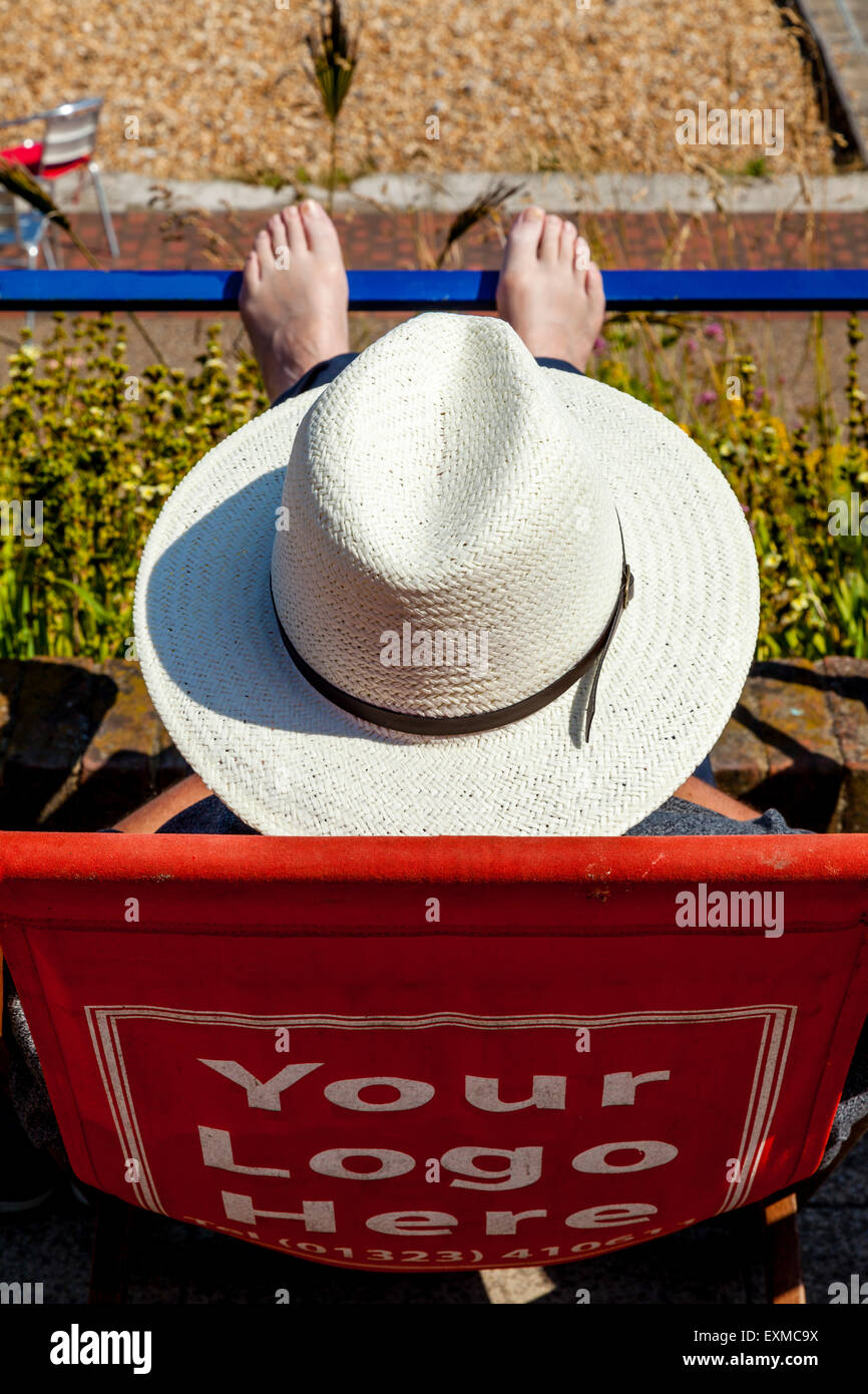 Un homme assis dans une chaise longue sur le front, Eastbourne, Sussex, UK Banque D'Images