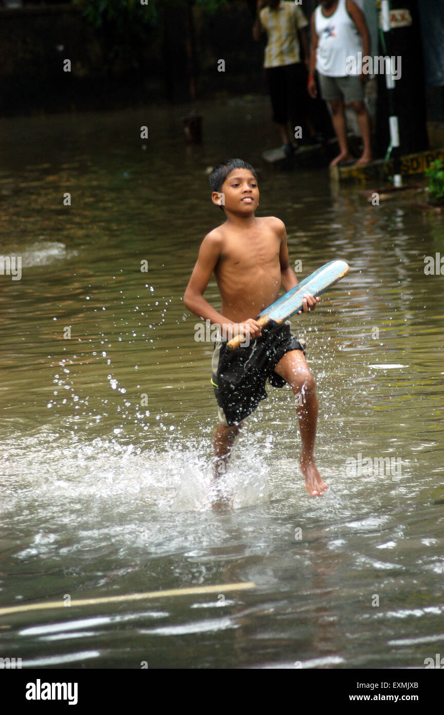 Inondations de pluie de mousson, garçon jouant au cricket inondé rue, Bombay, Mumbai, Maharashtra, Inde, Asie Banque D'Images