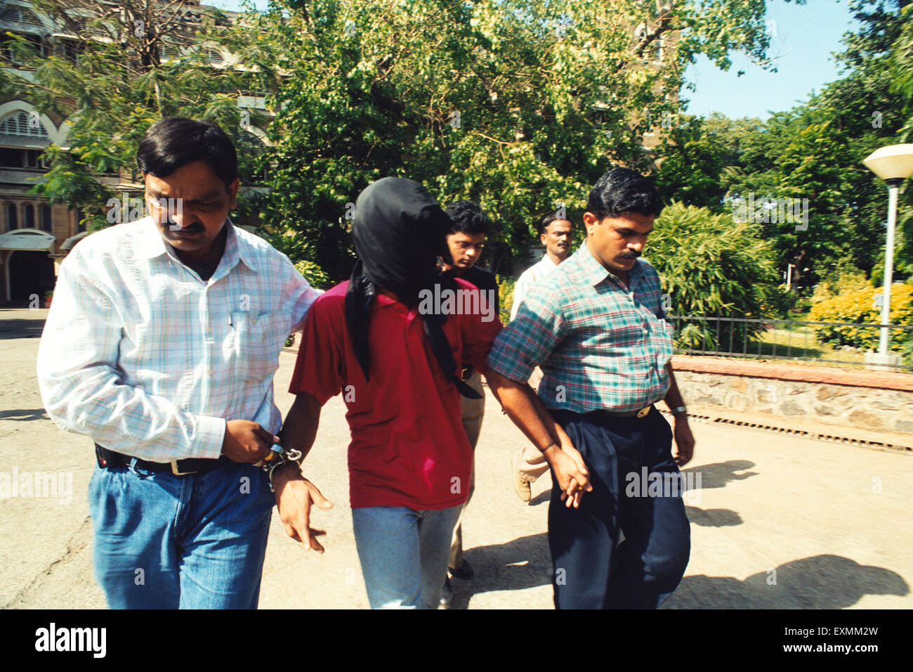 Masque couvert visage homme à capuche criminel attrapé police escortée Bombay Mumbai Maharashtra Inde Asie Banque D'Images