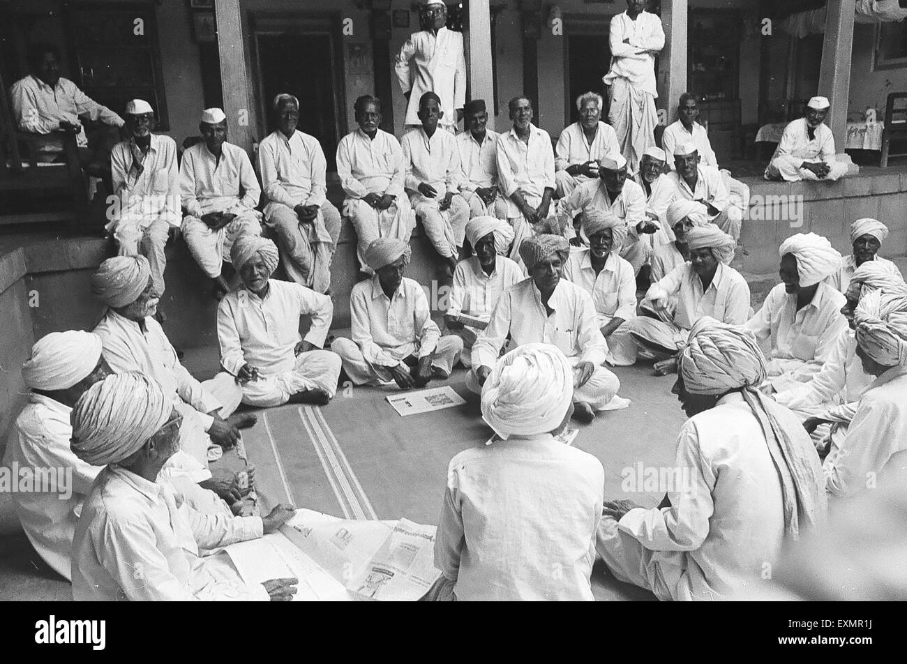Les villageois de Munagoli vêtus de turbans blancs traditionnels ou de casquettes blanches se réunissent dans la cour de la vieille maison du propriétaire Munjaili, Morena, Madhya Pradesh, Inde, Asie Banque D'Images