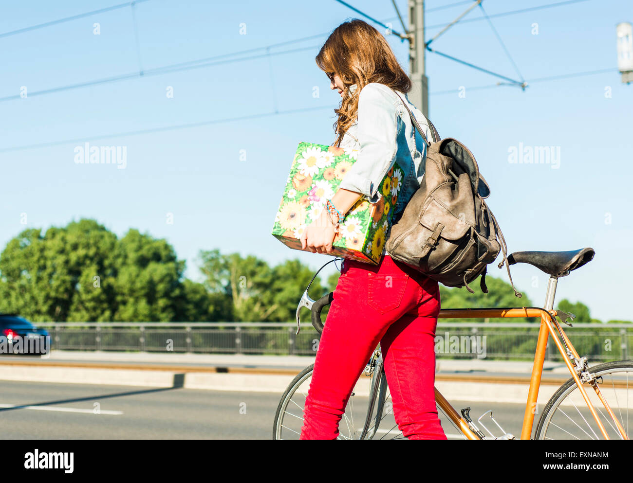 Jeune femme à vélo sur la rue holding gift box Banque D'Images