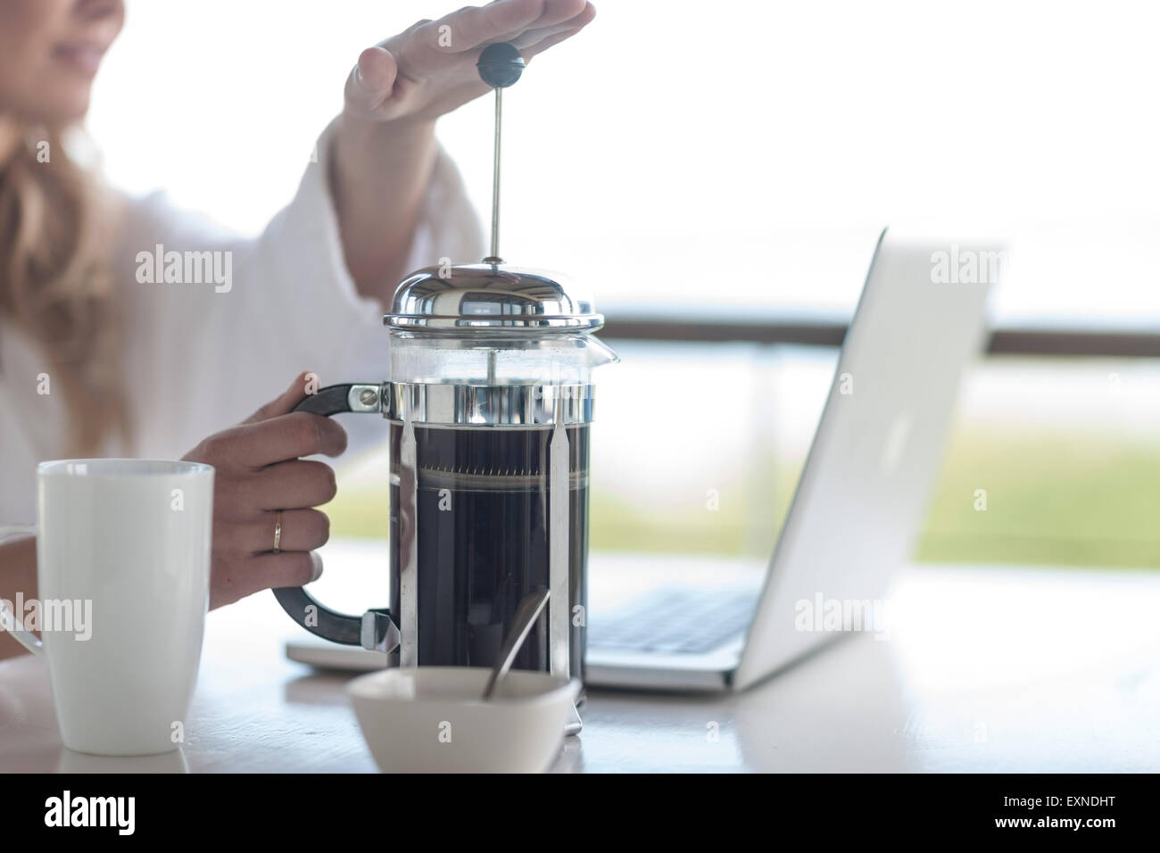 Close-up of woman avec une cafetière à piston à l'aide d'ordinateur portable Banque D'Images