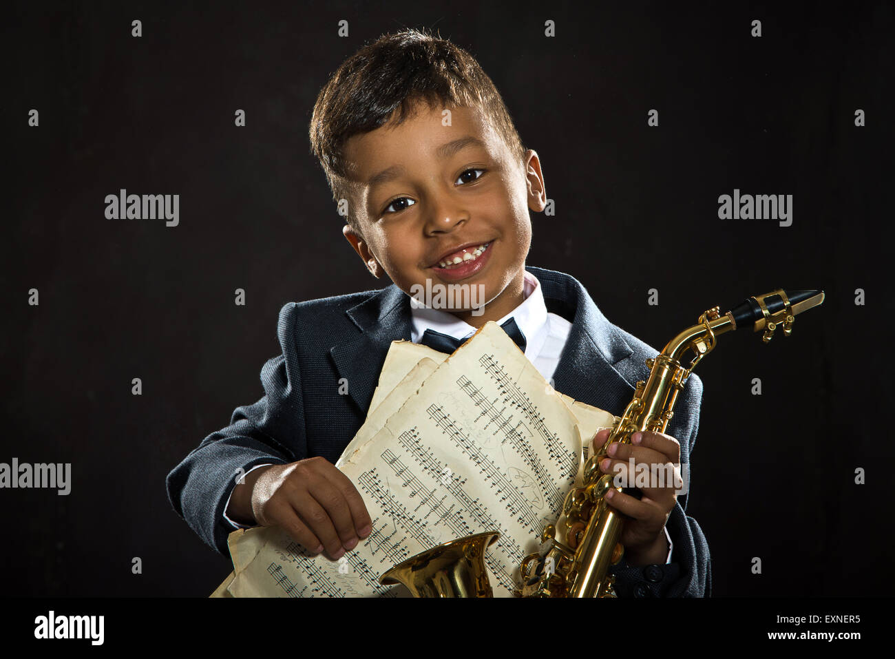 Un garçon de six ans s'asseoir avec le saxophone et sourire. close up portrait Banque D'Images