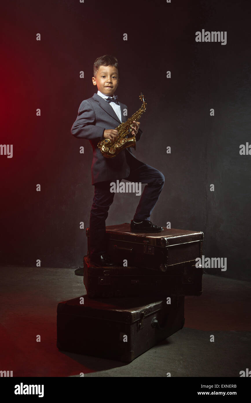 Un garçon de six ans avec le saxophone. instagrsm siuitcases vieux tonique Banque D'Images