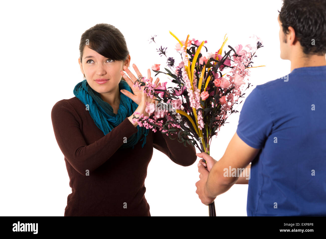 Hispanic couple combat comme on essaie de donner des fleurs pendant qu'elle pousse à l'écart avec l'expression du visage ennuyé Banque D'Images