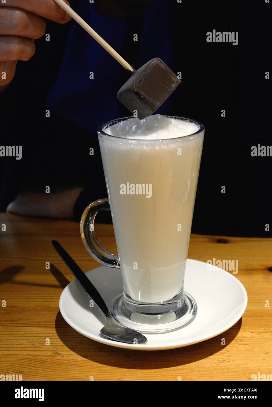 Faire une boisson chaude au chocolat en trempant du chocolat dans du lait chaud Banque D'Images