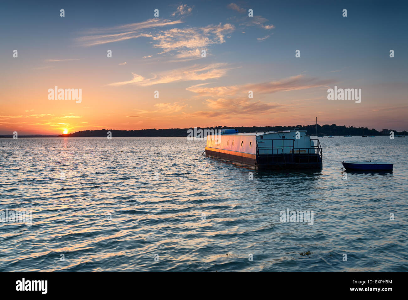 Maison bateau au coucher du soleil à flot sur la baie des ronces à Studland sur la côte du Dorset, donnant sur l'île de Brownsea Banque D'Images