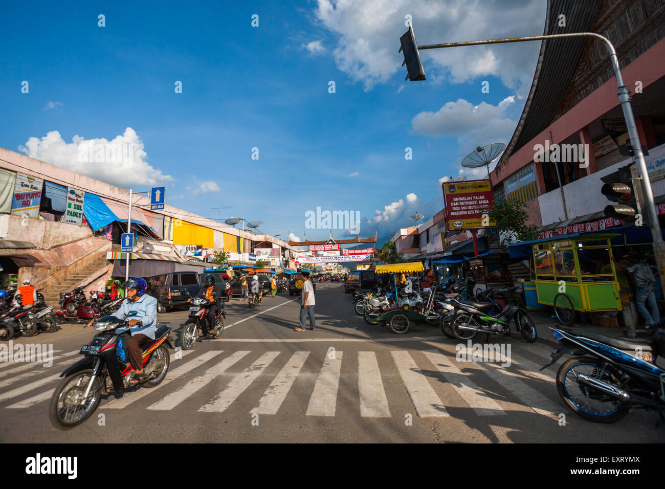 Un automobiliste sur la route, traversant une croix de zébra dans une zone commerciale de Payakumbuh, Sumatra Ouest, Indonésie. Banque D'Images