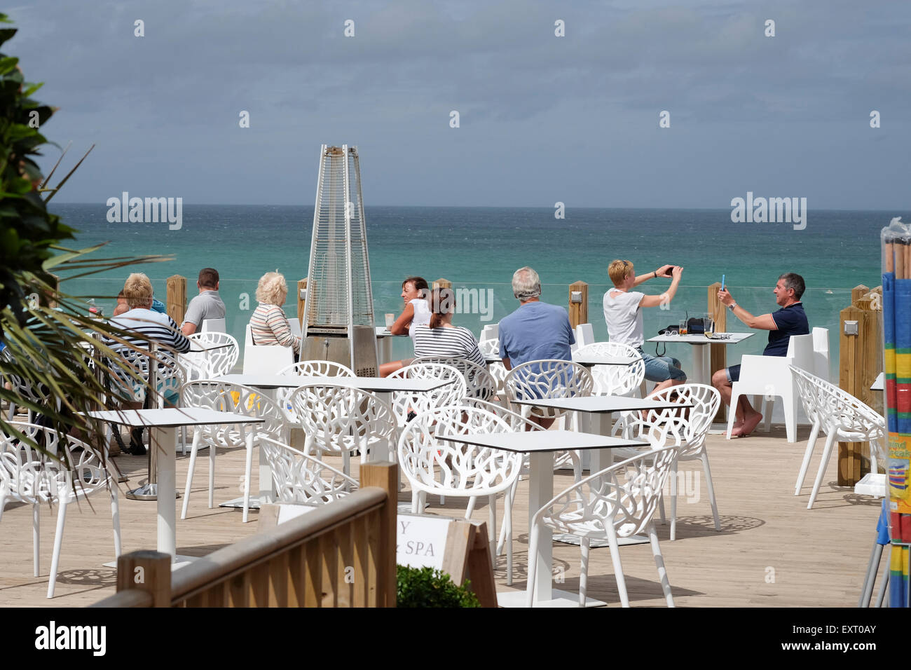 St Ives, Cornwall, UK : groupe de personnes de manger et prendre des photos à l'extérieur à Carbis Bay Café Banque D'Images
