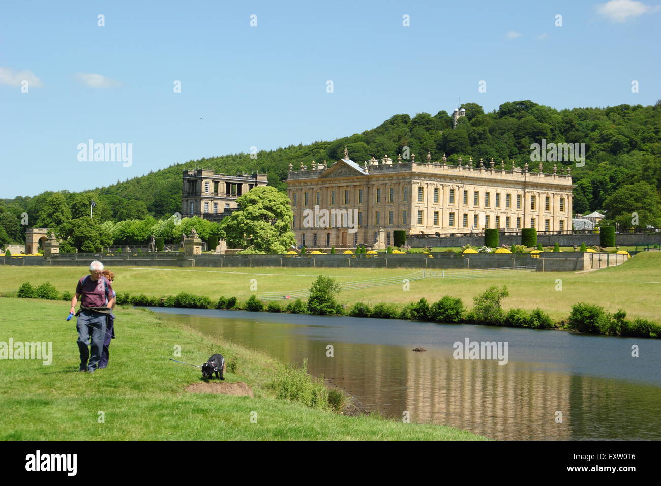 Deux hommes à pied sur les rives de la rivière Derwent par Chatsworth House dans le Peak District sur une magnifique journée d'été, Derbyshire, Royaume-Uni Banque D'Images