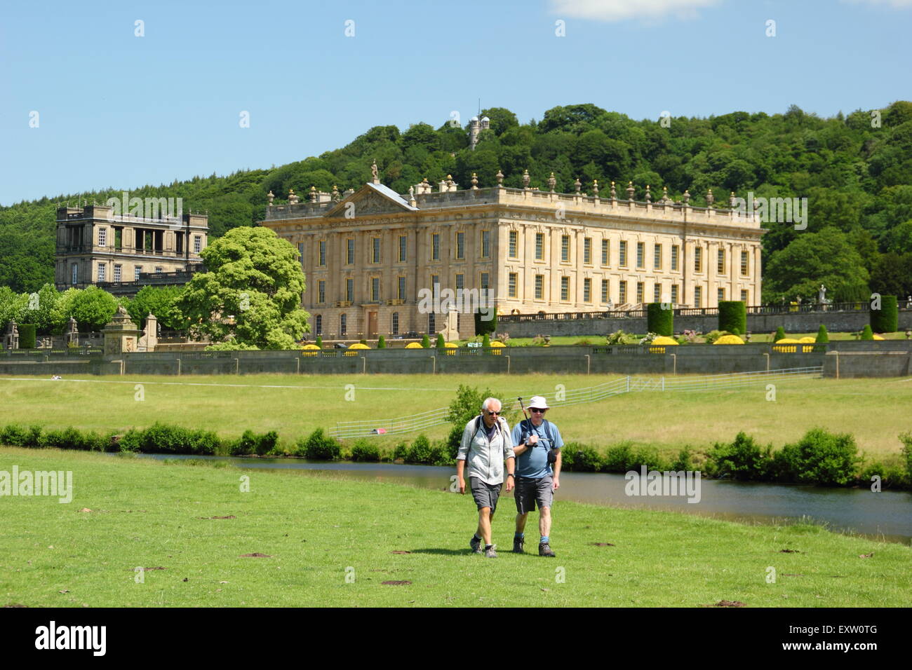 Deux hommes à pied sur les rives de la rivière Derwent par Chatsworth House dans le Peak District sur une magnifique journée d'été, Derbyshire, Royaume-Uni Banque D'Images