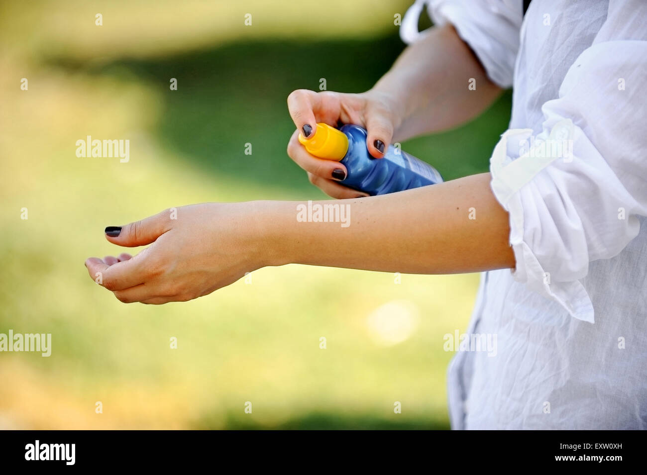Mains d'une femme à l'aide d'une bouteille bleue d'écran solaire Banque D'Images