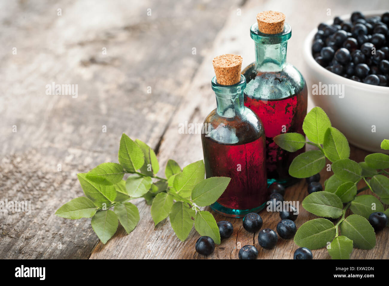 Flacons de teinture ou de produit cosmétique et le bol de myrtilles sur table en bois. Banque D'Images