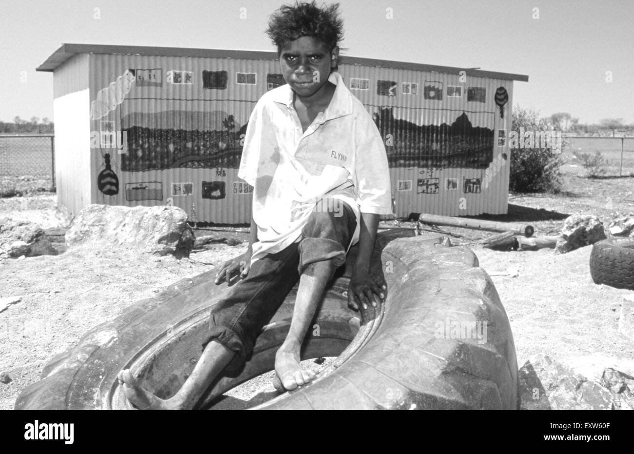 Teenage boy sitting autochtones sur le pneu, Yuelamu (Mount Allan) dans le Territoire du Nord, Australie Banque D'Images