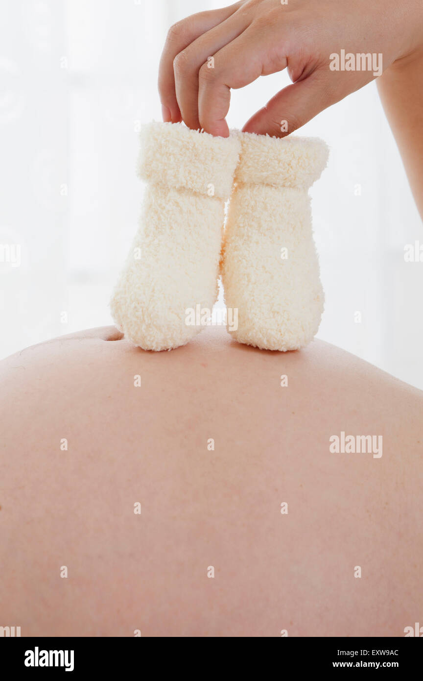 Pregnant woman holding Baby socks sur l'abdomen, Banque D'Images