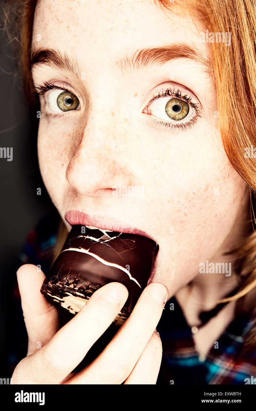 Girl eating a guimauves enrobées de chocolat , Allemagne Banque D'Images