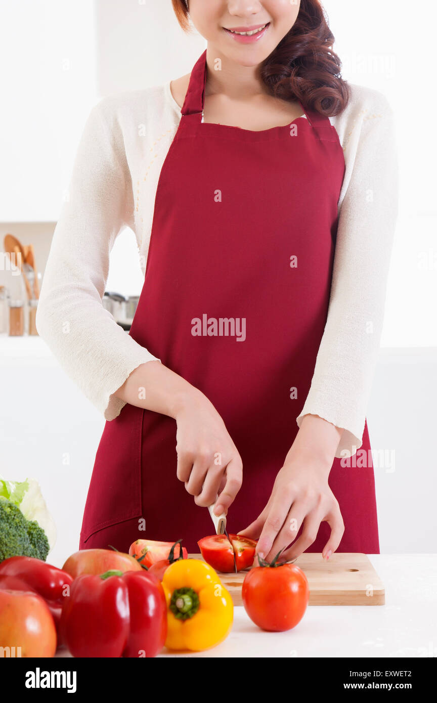 Jeune femme couper des légumes avec sourire, Banque D'Images