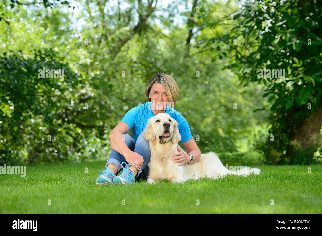 Femme mature avec un golden retriever dans jardin Banque D'Images