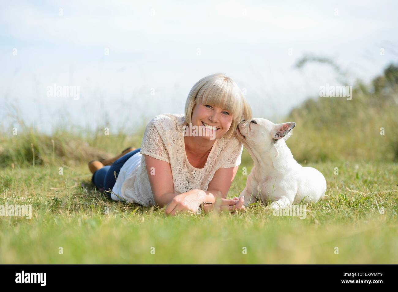 Femme couchée sur prairie avec un sept mois Bouledogue Français Banque D'Images