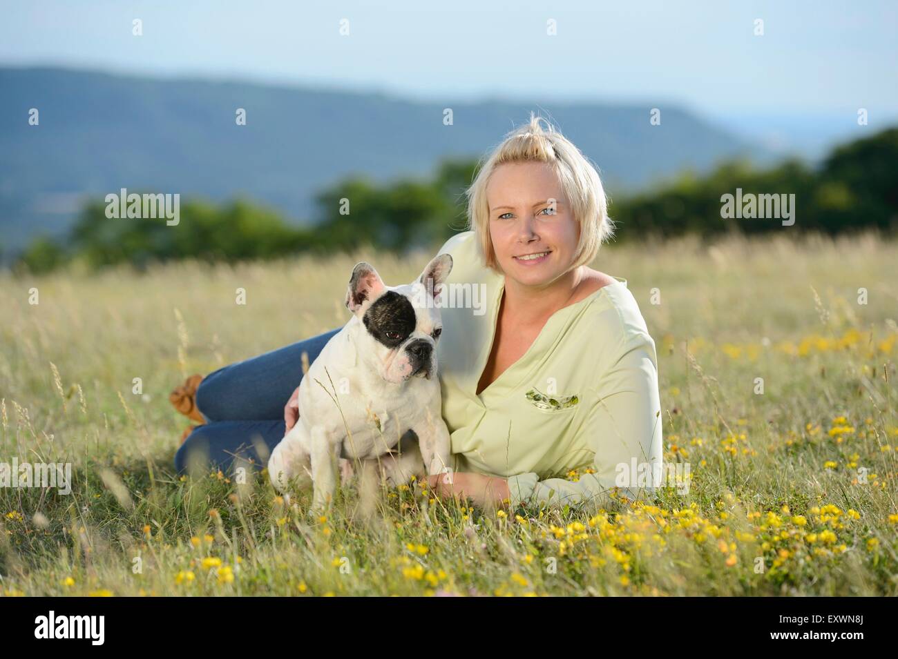 Femme couchée sur prairie avec un sept mois Bouledogue Français Banque D'Images