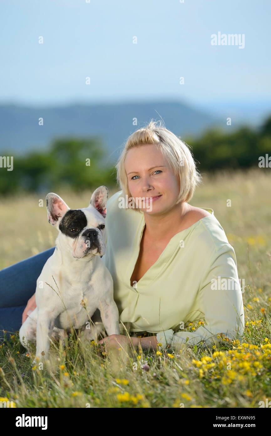 Femme couchée sur prairie avec un sept mois Bouledogue Français Banque D'Images