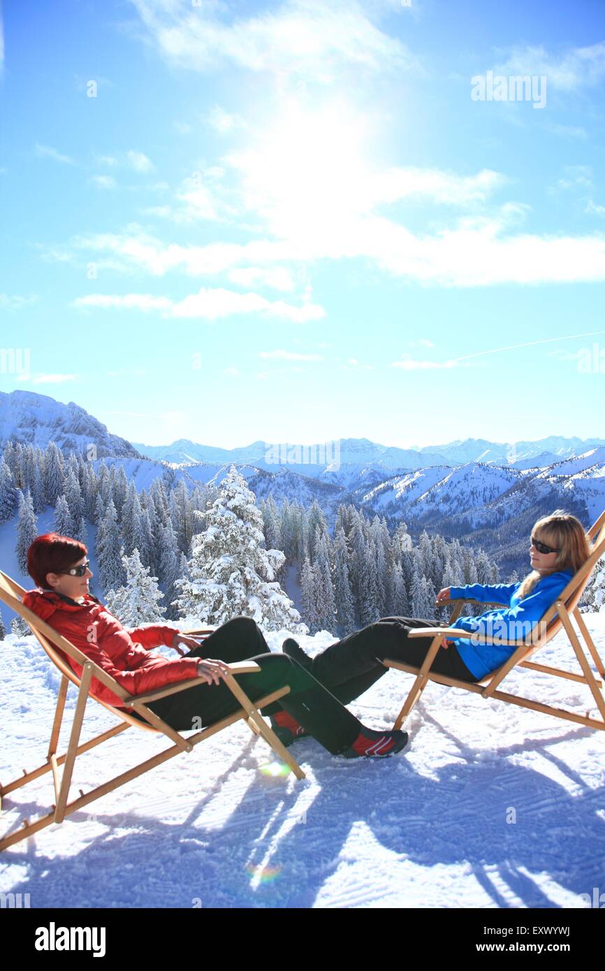 Deux femmes dans une chaise longue dans la neige, Alpes, Tegelberg, Allgaeu, Bavaria, Germany, Europe Banque D'Images