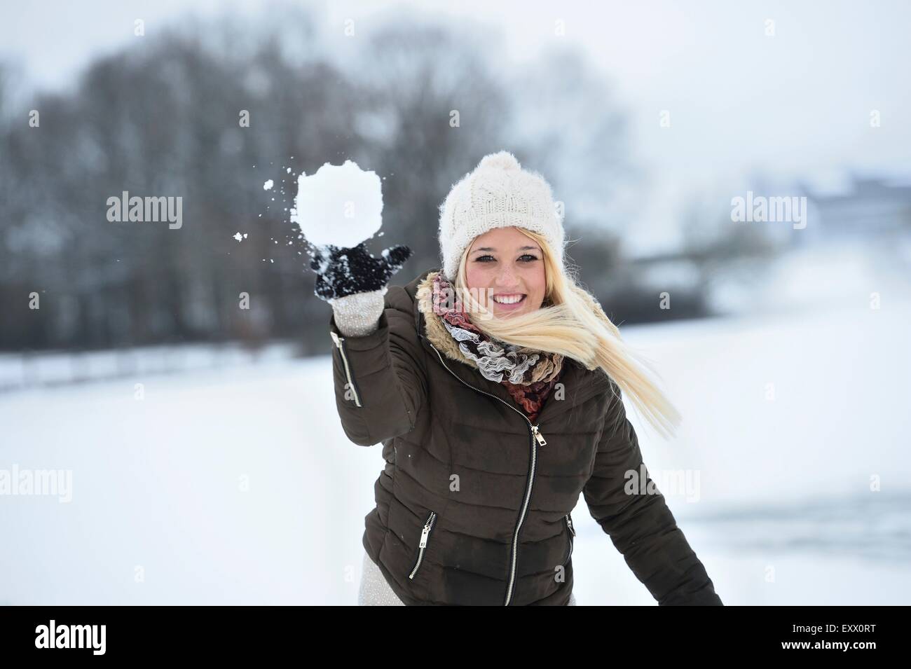 Jeune femme heureuse de lancer une balle de neige Banque D'Images
