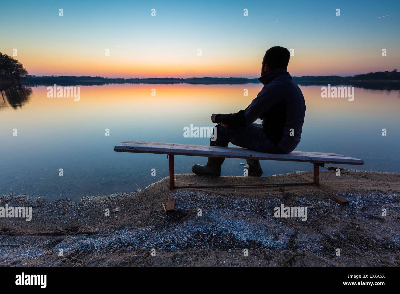 L'homme dans l'eau du lac au coucher du soleil. Magnifique coucher de soleil avec l'homme d'ossature Banque D'Images