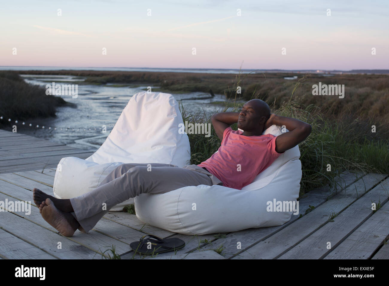 Man relaxing on dock au bord de l'eau Banque D'Images