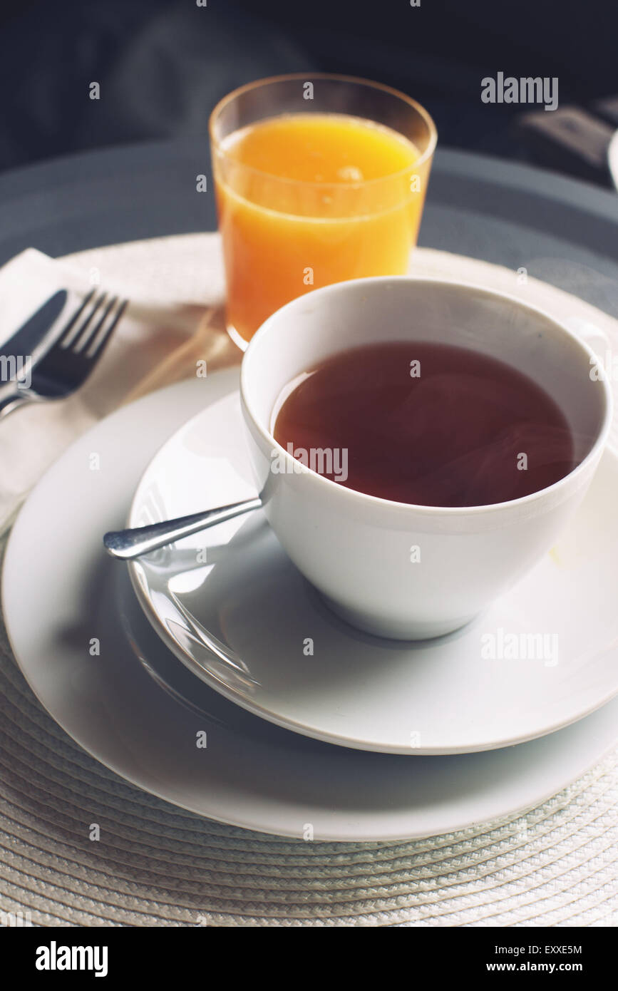 Tasse de thé chaud et verre de jus d'orange Banque D'Images