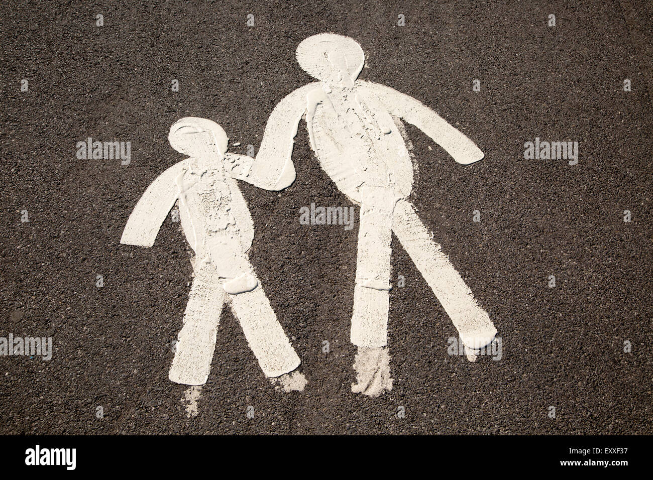 Les chiffres de l'enfant et le parent se tenant la main sur la chaussée goudronnée, marmonne, South Wales, UK Banque D'Images