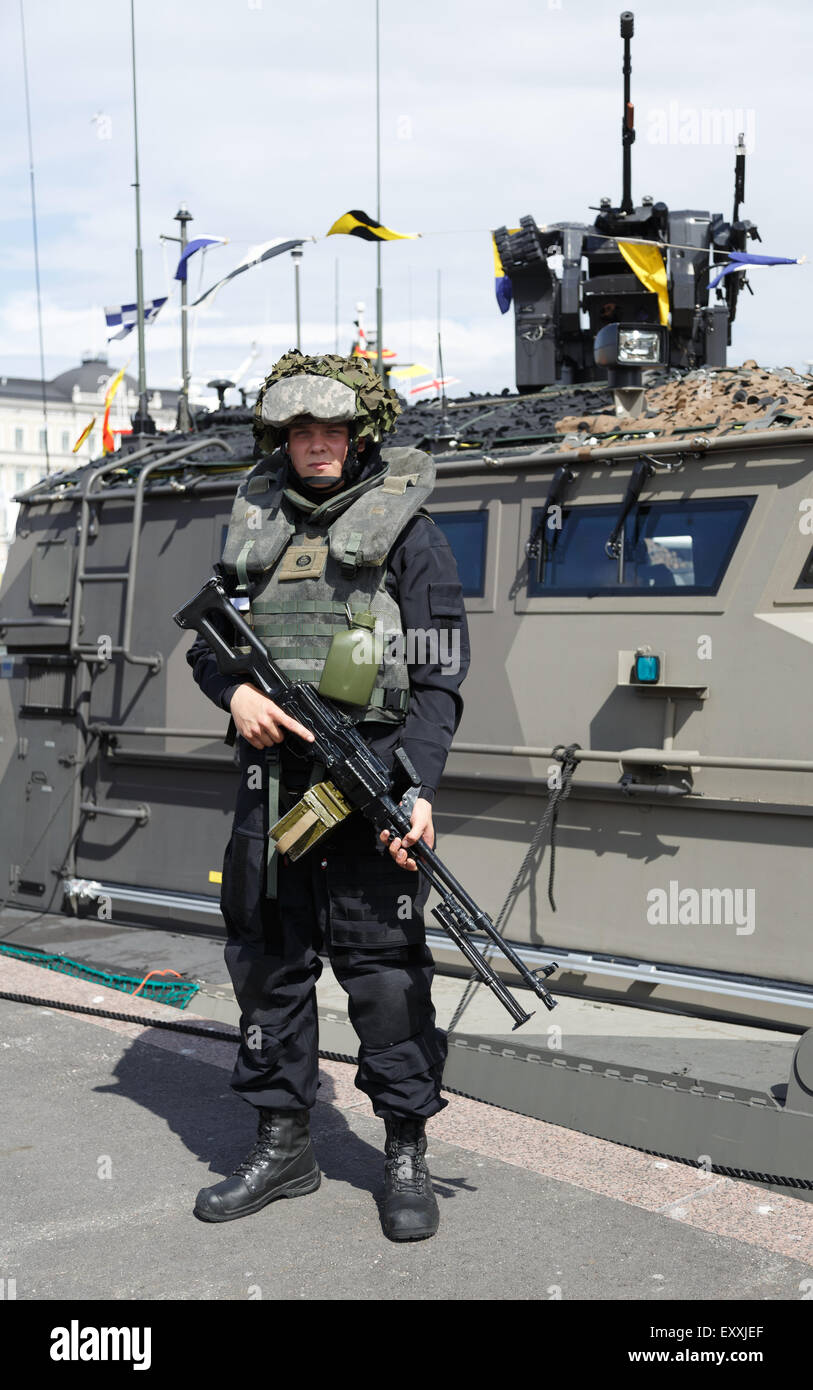 Coastal Jaeger de la marine finlandaise posant avec sa mitraillette en face d'une classe-Jéhu transports bateau sur la Journée de la Marine. Banque D'Images