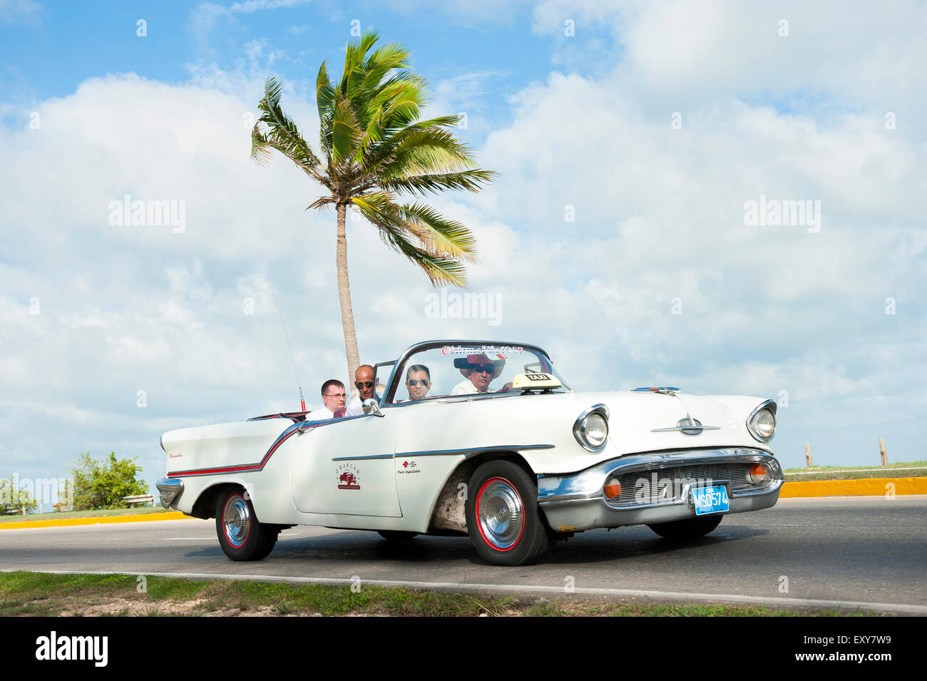 VARADERO, CUBA - 07 juin 2011 : les touristes ride en blanc Classic vintage American car la conduite sur une route côtière avec palmier. Banque D'Images