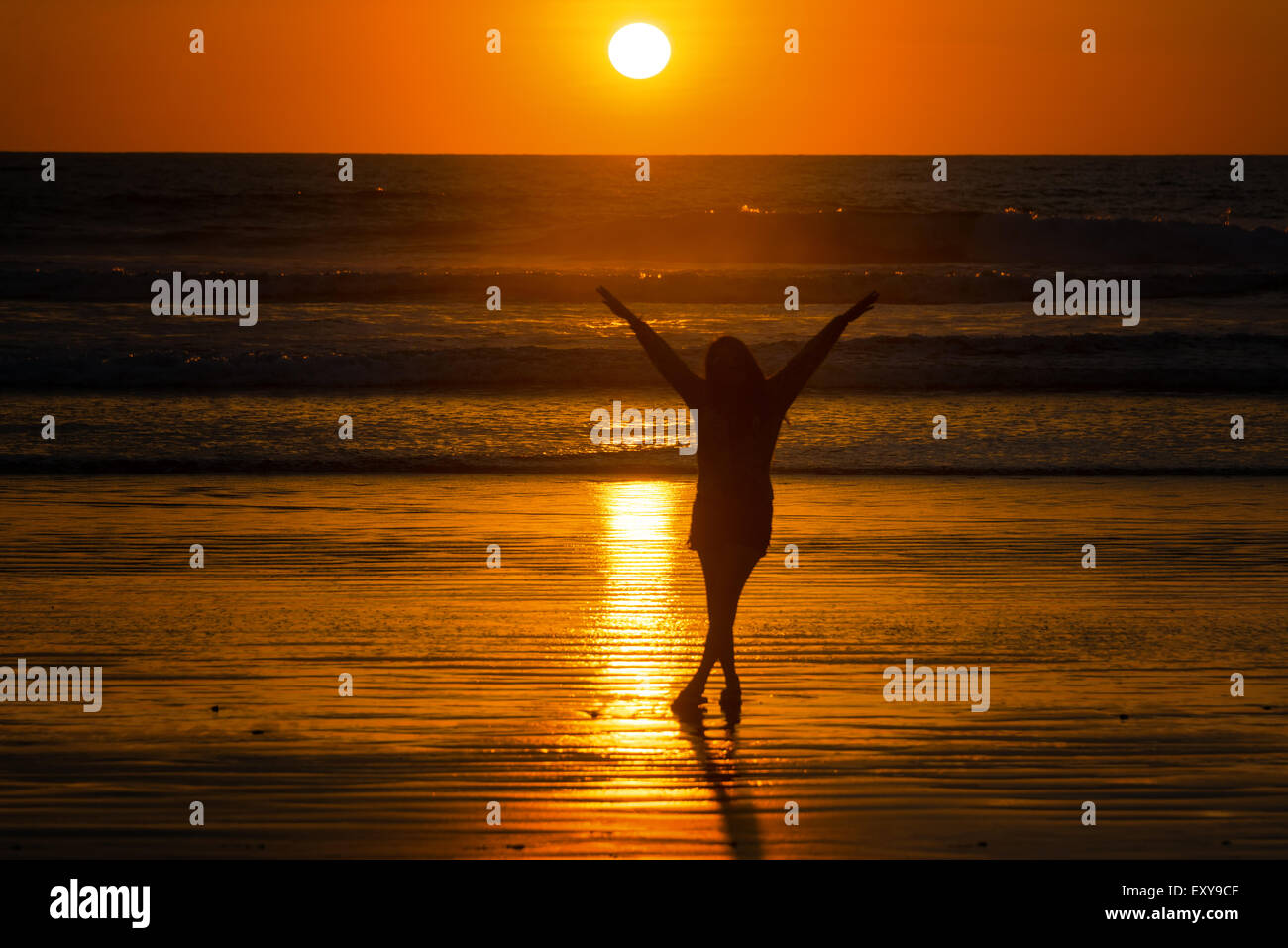 Silhouette d'une belle jeune femme sur une plage de Punta Montañita, Équateur au coucher du soleil Banque D'Images