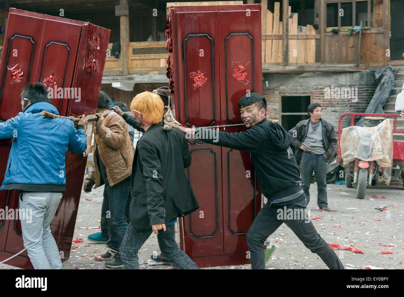 Les jeunes, couverts de suie firecracker transportant des meubles de mariage, village Dong de Huanggang, province de Guizhou, Chine Banque D'Images