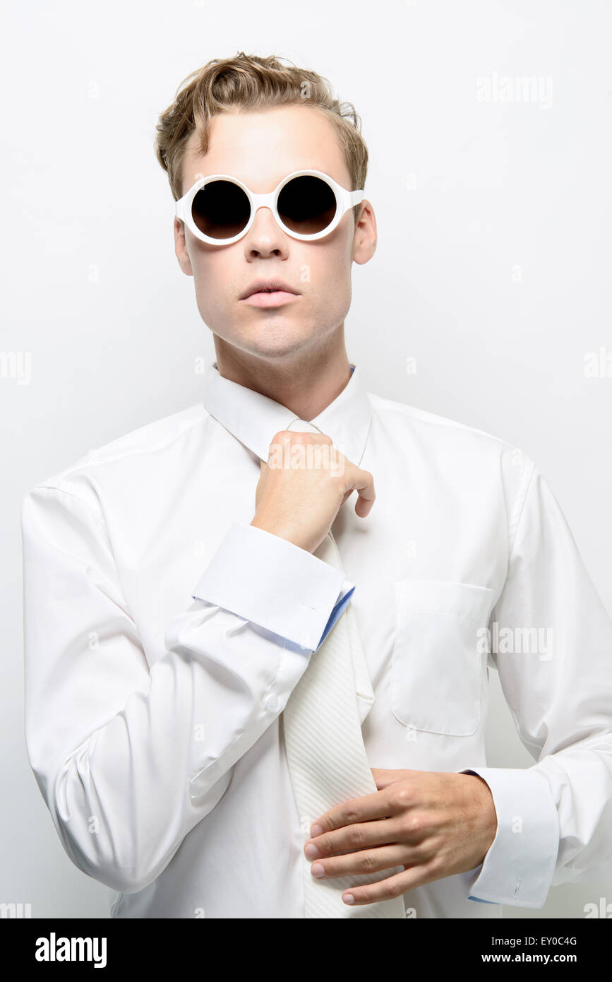 Un jeune homme, modèle masculin, adjusting necktie, portant un costume tout  blanc et lunettes de soleil. Un concept futuriste, concept de haute couture  Photo Stock - Alamy