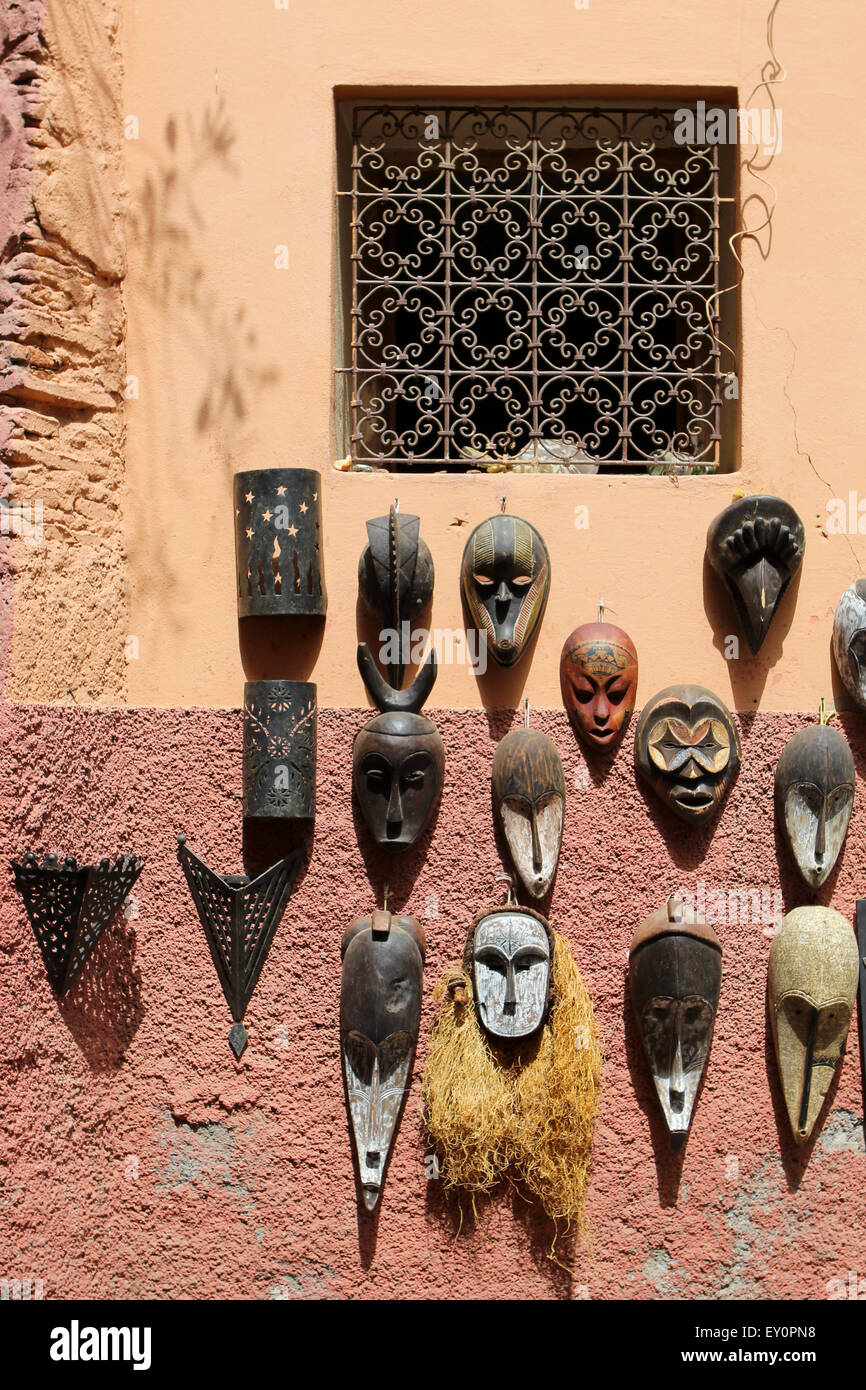 Les masques en bois peint de l'Afrique de l'accrocher sur un mur sous une arabesque fenêtre de détail à Marrakech, Maroc Banque D'Images